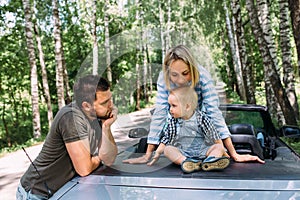 Mom, dad and little son in a convertible car. Summer family road trip to nature