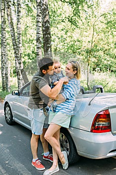 Mom, dad and little son in a convertible car. Summer family road trip to nature