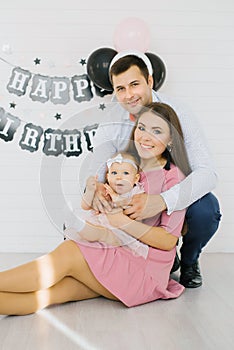 Mom, dad and one-year-old girl in the photo zone for the first birthday of the baby. Portrait of a happy family