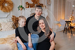 mom, dad and son in black robes on a bed in a white room. happy family.