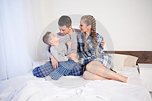 Mom dad and son in the morning in the bedroom on the bed