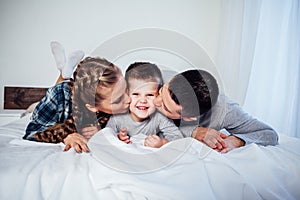 Mom dad and son in the morning lying on the bed at home in a good mood