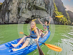 Mom, dad and son travelers rowing on a kayak in Halong Bay. Vietnam. Travel to Asia, happiness emotion, summer holiday