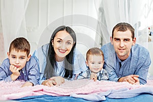 Mom, dad and two young children lying on the bed. The concept of