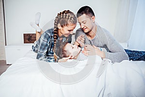 Mom dad and son in the morning lying on the bed at home in a good mood