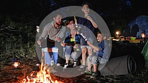 Mom and daddy with kids resting to campground and roast zephyr on bonfire, parents with childs broil marshmallow