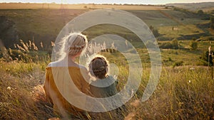 Mom and daughter 6 years look together at sunset