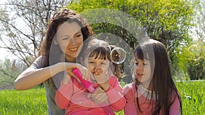 Mom and daughter blow bubbles. Family in the park. Children with mom are playing with bubbles.