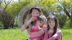 Mom and daughter blow bubbles. Family in the park. Children with mom are playing with bubbles. Happy family in nature.