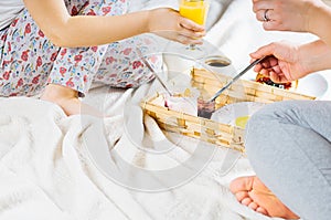 Mom and daughter breakfast in bed on a white blanket