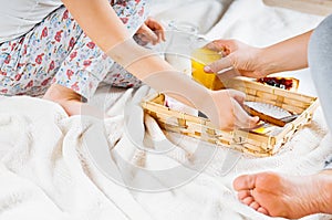 Mom and daughter breakfast in bed on a white blanket