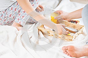 Mom and daughter breakfast in bed on a white blanket