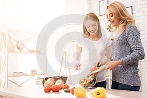 Mom and daughter are cooking together in the kitchen.