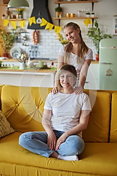 Mom and daughter on the couch on Mother& x27;s Day looking at the camera