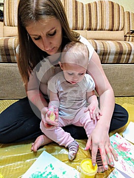 Mom and daughter do handprints with yellow paint