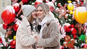 Mom and daughter with dog Papillon near Christmas tree on street. photo shoot