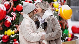 mom and daughter with dog Papillon near Christmas tree on street. photo shoot