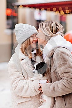 mom and daughter with dog Papillon near Christmas tree on street. photo shoot