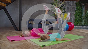 Mom and daughter doing leg lowers exercise indoors