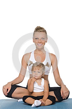 Mom and daughter doing yoga on mat