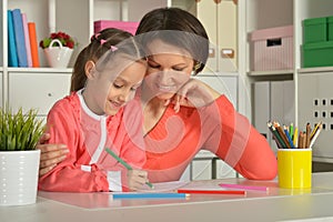 Mom and daughter draw at home together.