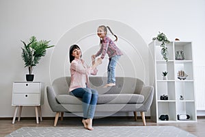 Mom-daughter duo testing bounce of couch in family lounge