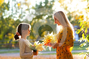 Mom with daughter are holding bouquetes of autumn leaves in the park photo