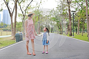 Mom and daughter holding hands in the outdoor nature garden