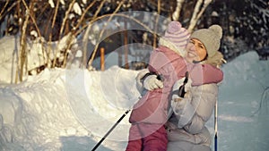 Mom and daughter hug after nordic walking in the suburbs in winter.