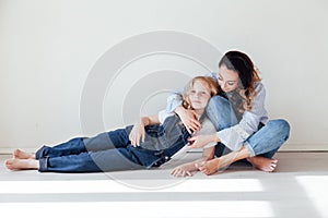 Mom and daughter in jeans cuddle laughing