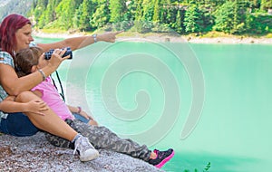 mom and daughter look at something with binoculars during an excursion to the lake