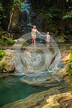 Mom and daughter on a mountain river under a waterfall in the jungle.Turkey