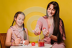 Mom and daughter paint eggs for Easter. A believing woman and a child girl preparing for a religious holiday