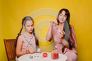 Mom and daughter paint eggs for Easter. A believing woman and a child girl preparing for a religious holiday