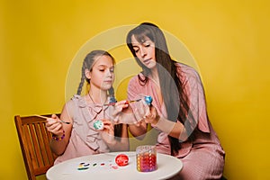 Mom and daughter paint eggs for Easter. A believing woman and a child girl preparing for a religious holiday