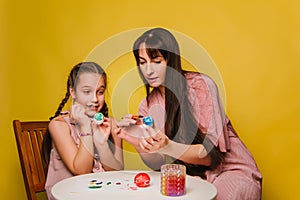 Mom and daughter paint eggs for Easter. A believing woman and a child girl preparing for a religious holiday