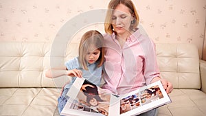mom and daughter with a photobook with photos of a pregnancy family photo shoot