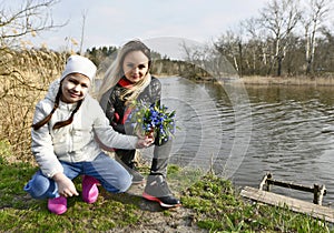 Mom and daughter pick the first spring flowers.