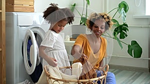 Mom and daughter play with clothes have fun and bonding time near washing machine indoors Spbd.