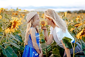 Mom and daughter play in the field of sunflowers