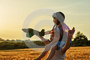 Mom and daughter playing in the field at sunset with a model aircraft .