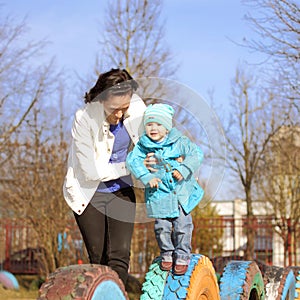 Mom and daughter playing on the playground. Beautiful young mother playing with her baby on the playground