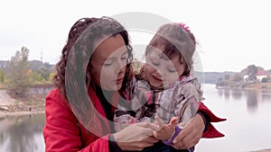 Mom and daughter are playing on the river bank. A little girl with her mother at the river plays together.