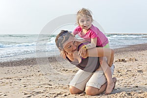 Mom and daughter plays on the beach