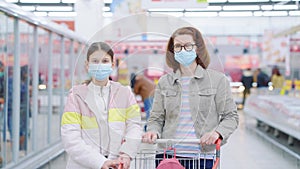 Mom and daughter posing in supermarket during pandemic