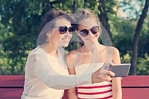 Mom and daughter, relationship between parent and teenager, outdoor portrait of mother with girl having fun, taking photos on mobi