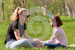 Mom and daughter rest on the green grass