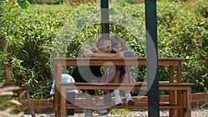 Mom and daughter are resting in the park in the recreation area. The family plays games on the phone