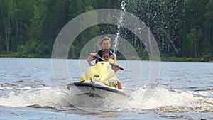 Mom and daughter ride along the river on a personal watercraft.