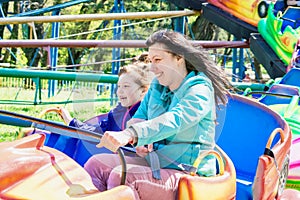 Mom and daughter ride an attraction. Woman and little girl have fun in an amusement park. Family riding a rollercoaster